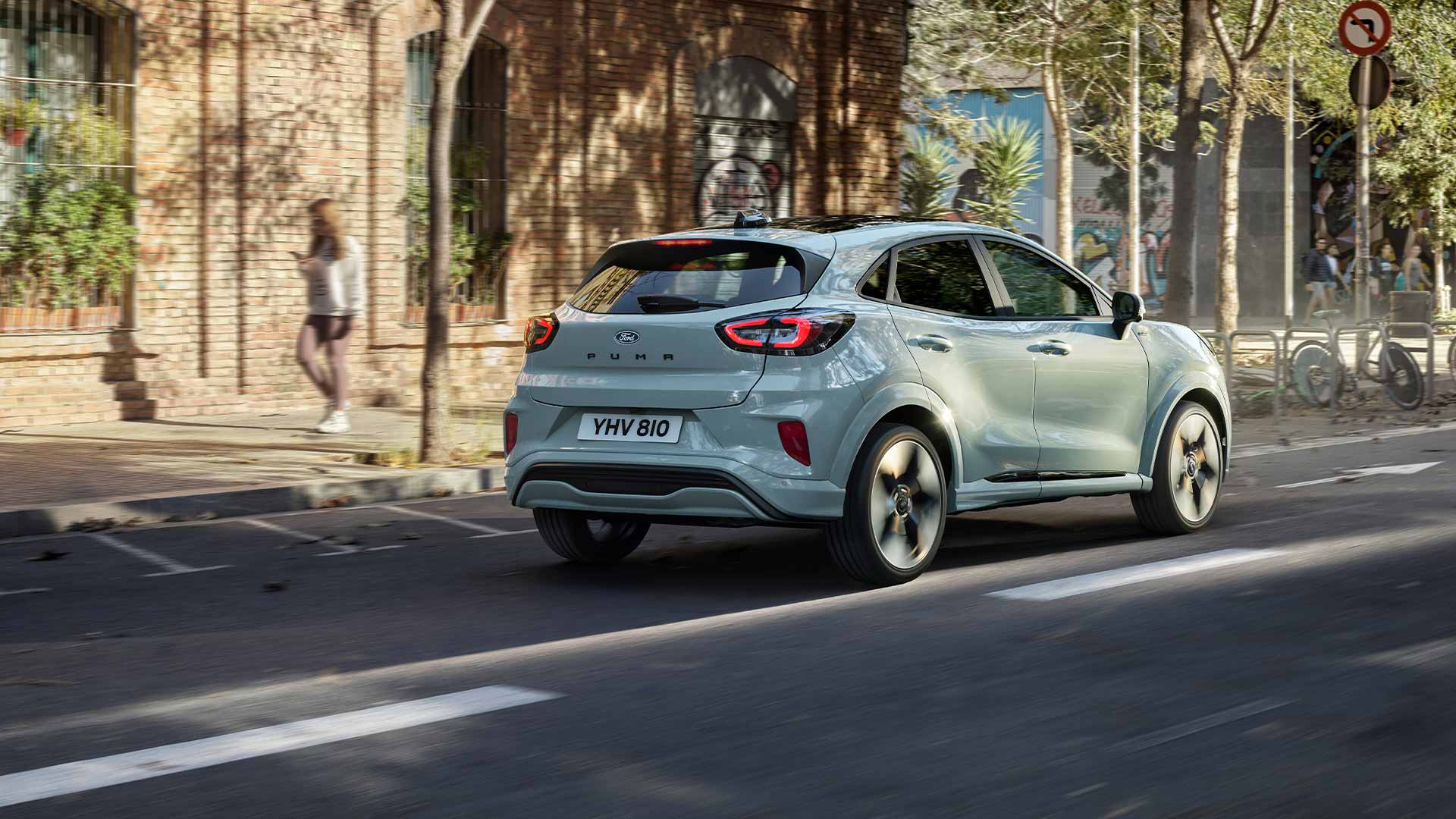 Ford Puma in Grau. Heckansicht, fährt auf einer Straße.