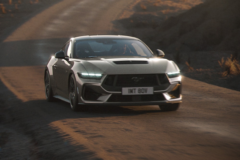 : Ford Mustang GT in Grau. Frontansicht, fahrend auf einer unebenen Straße.