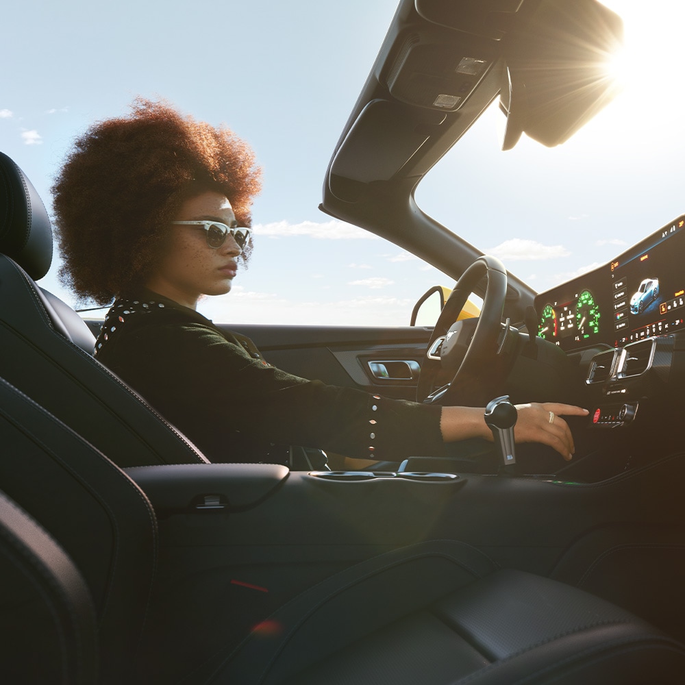 Ford Mustang Innenraum. Ansicht auf Vordersitz und Instrumententafel. Frau sitzt im Fahrersitz.