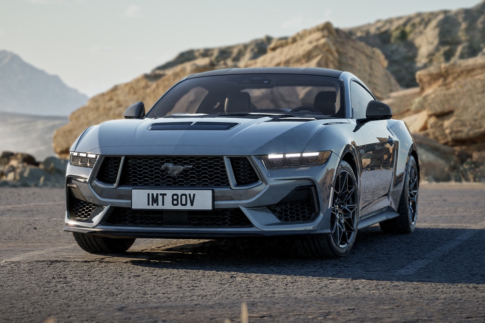 : Ford Mustang GT in Grau. Frontansicht, fahrend auf einer unebenen Straße.
