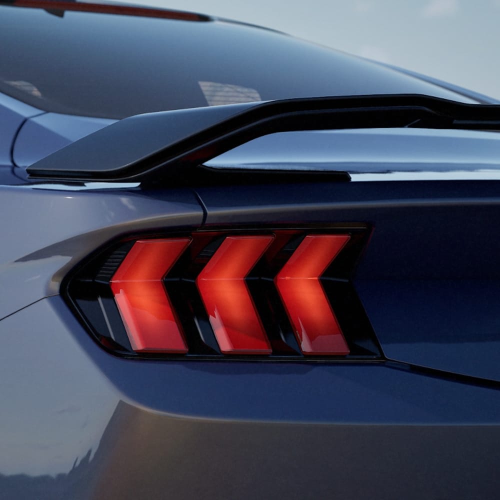 Ford Mustang in Blau. Heckansicht, stehend auf einem Parkplatz bei Sonnenuntergang.