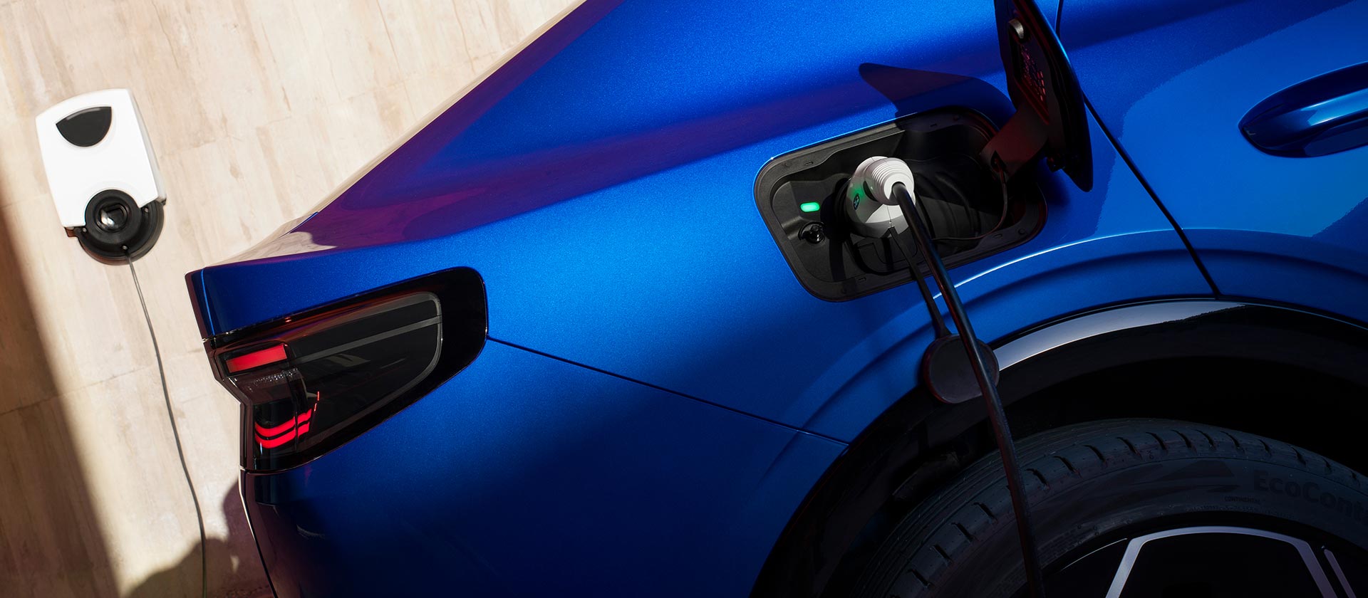 Ford Capri in Blau. Detailansicht Ladeanschluss mit angeschlossenem Ladekabel.