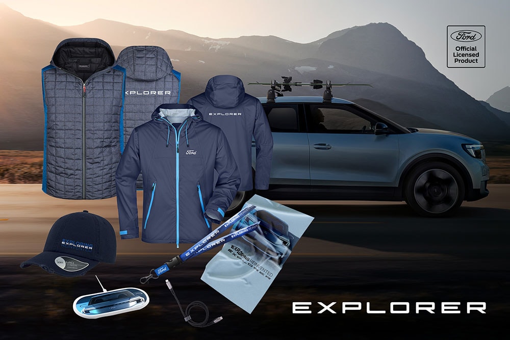Ford Explorer Werbeartikel in Blau- und Grautönen vor einem blauen Ford Explorer: Jacken, Lanyard und Kappe.