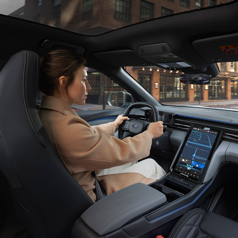 Ford Explorer Innenraum. Ansicht auf Lenkrad, Ford SYNC Move-Touchscreen und Panoramadach. Frau sitzt im Fahrersitz.