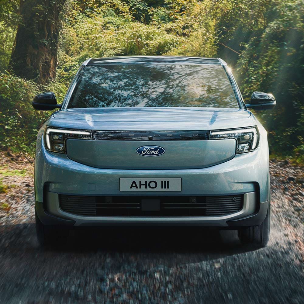 Ford Explorer in Blau. Frontansicht, fährt in einem Wald auf einer Schotterstraße.