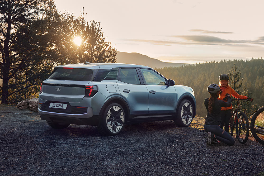 Ford Explorer in Blau. Dreiviertelansicht, stehend auf einem Hügel mit Bergen im Hintergrund.