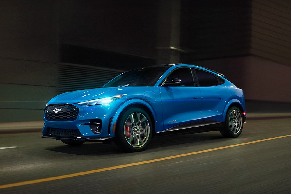 Ein blauer Ford Mustang Mach-E GT Elektro-Sportwagen fährt auf einer Straße.