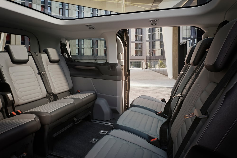 Ford Tourneo Custom Kleinbus mit geöffneter Schiebetür. Detailansicht des Innenraums und der flexiblen Dreireihensitzbank.