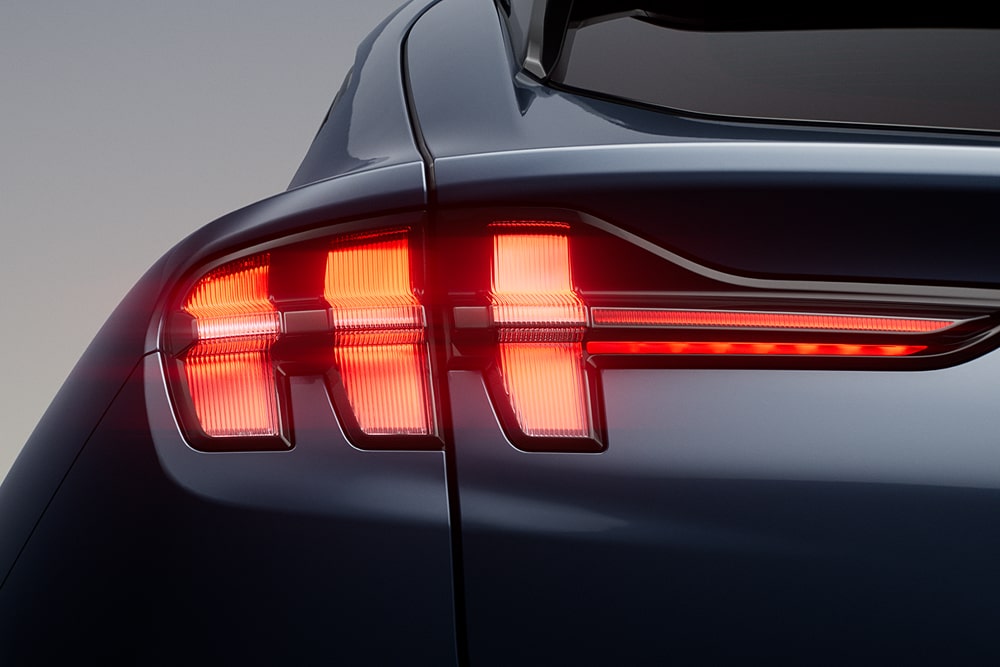 Ford Mustang Mach-E in Schwarz. Nahaufnahme der beleuchteten dreiteiligen Rückleuchten des Performance-Modells.