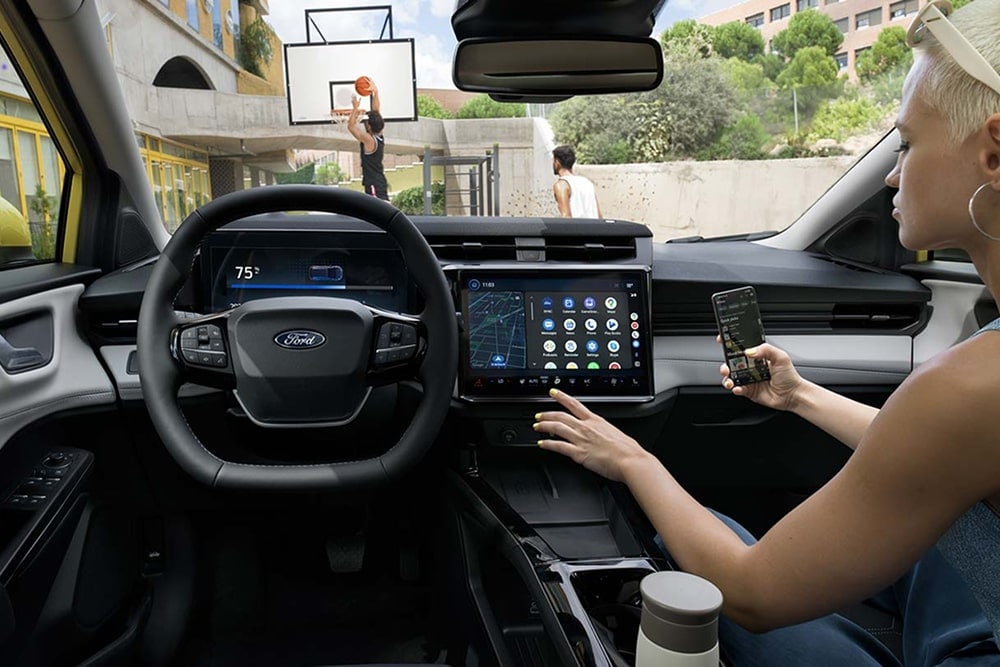 Ford Puma aus dem Sortiment der Ford Kleinwagen, Innenraumansicht. Eine Person bedient den Touchscreen.