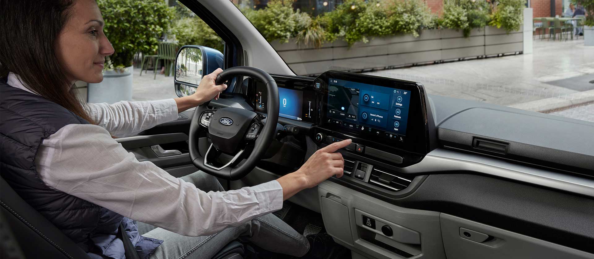 Ford Tourneo Custom Innenraum. Ansicht auf Instrumententafel. Frau bedient Ford SYNC 4-Touchscreen.