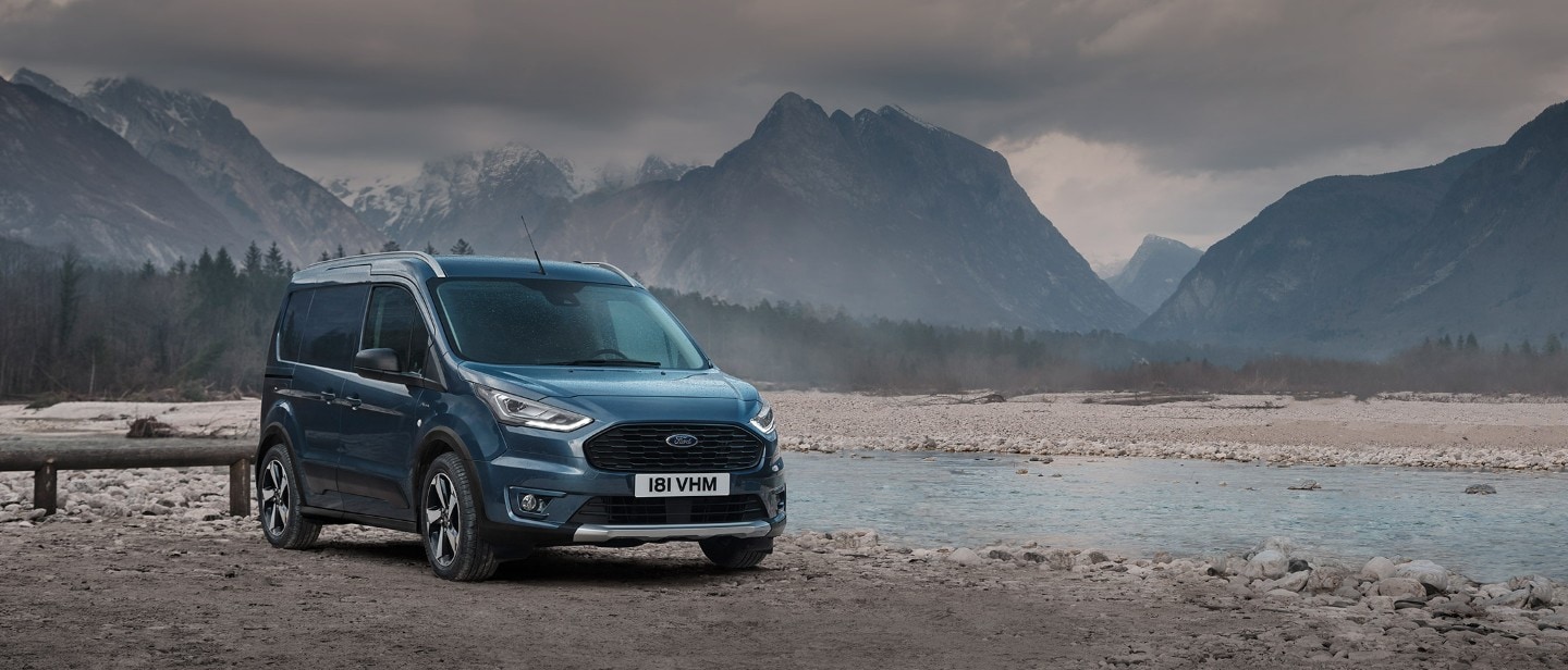 Ford Transit Connect in Blau. Dreiviertelansicht, vor einem See mit Bergen im Hintergrund