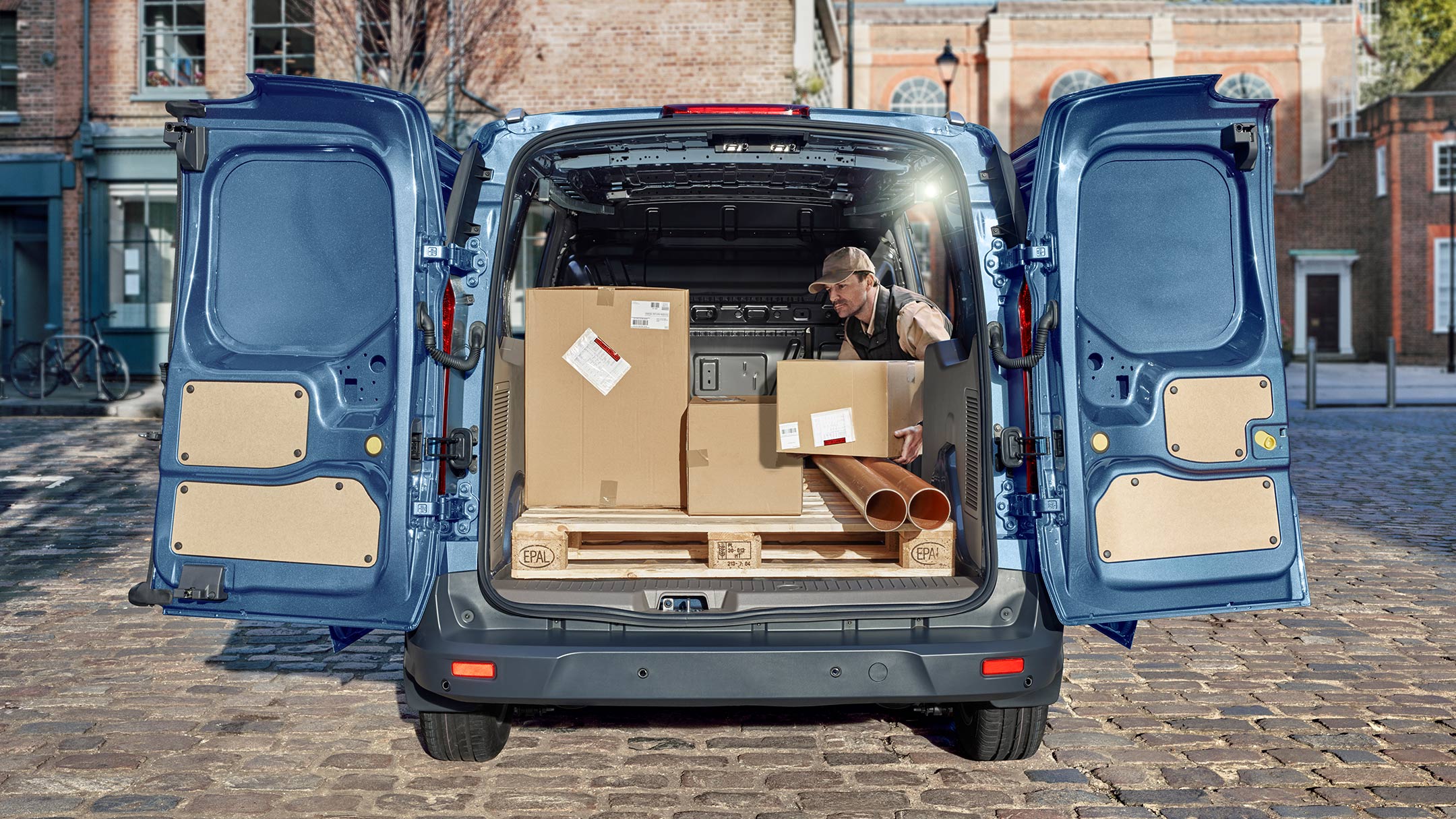 Ford Transit Connect in Blau. Heckansicht mit weit geöffneten Hecktüren wird entladen