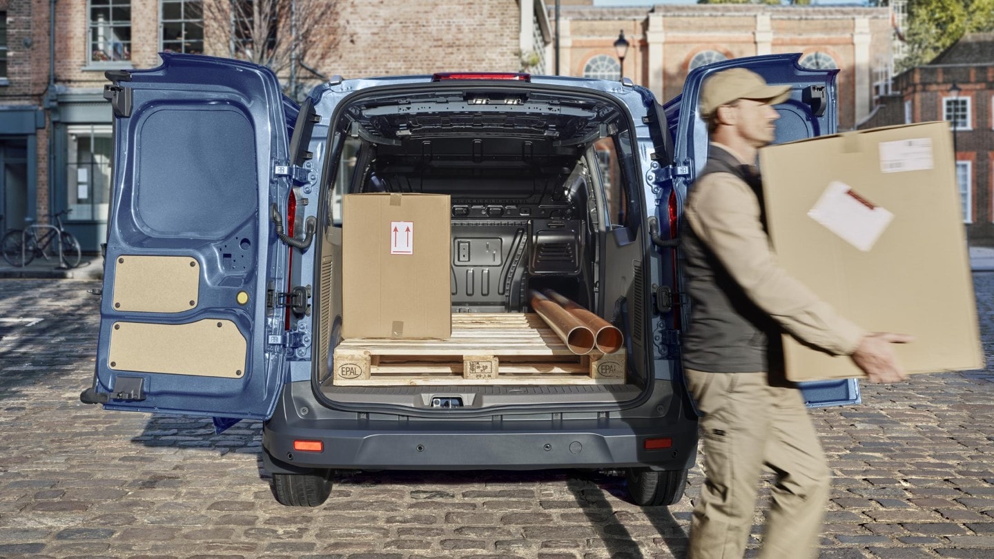 Ford Transit Connect in Blau. Heckansicht, parkend mit weit geöffneten Hecktüren. Mann entlädt das Fahrzeug