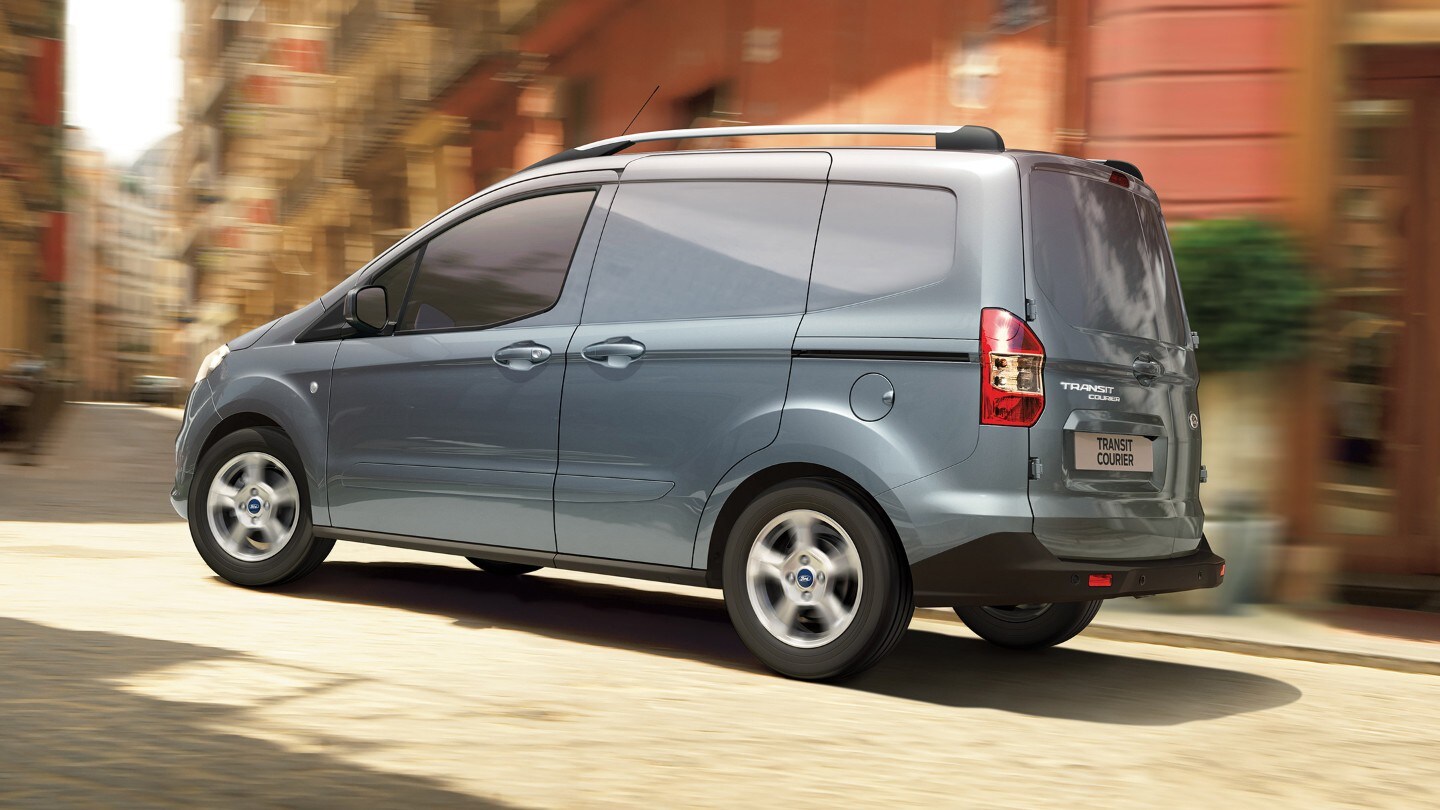 Ford Transit Courier in Blau. Seitenansicht, fahrend durch enge Straßen in der Innenstadt
