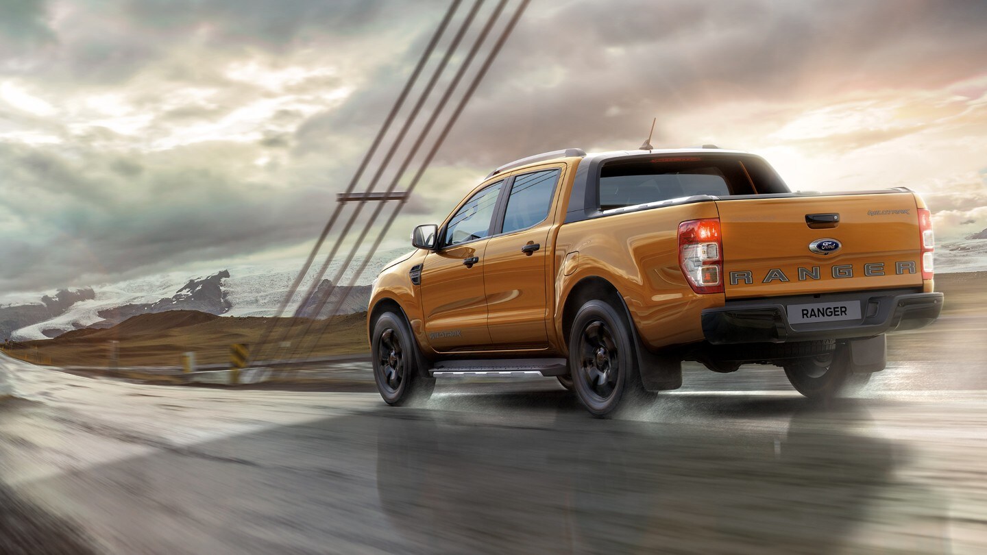 Ford Ranger in Orange. Heckansicht, auf einer Brücke fahrend