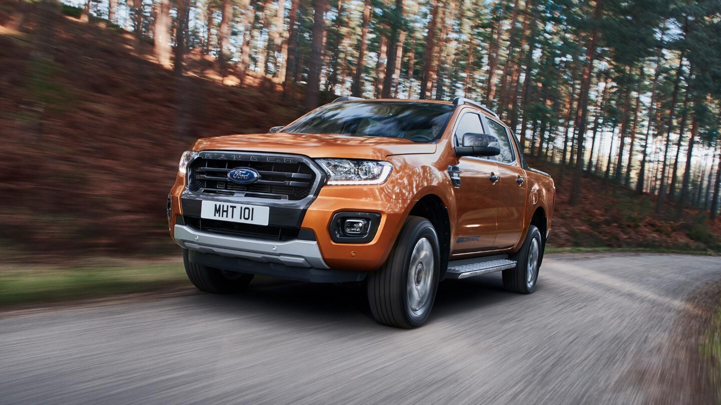 Ford Ranger in Orange. Frontansicht, in Bewegung auf bewaldeter Straße