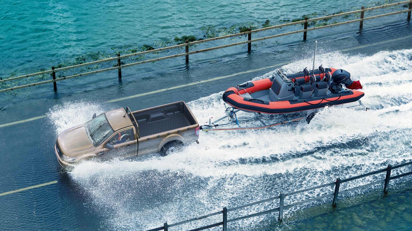 Ford Ranger in Silber. Ansicht von oben, zieht Anhänger mit Speedboot aus dem Wasser