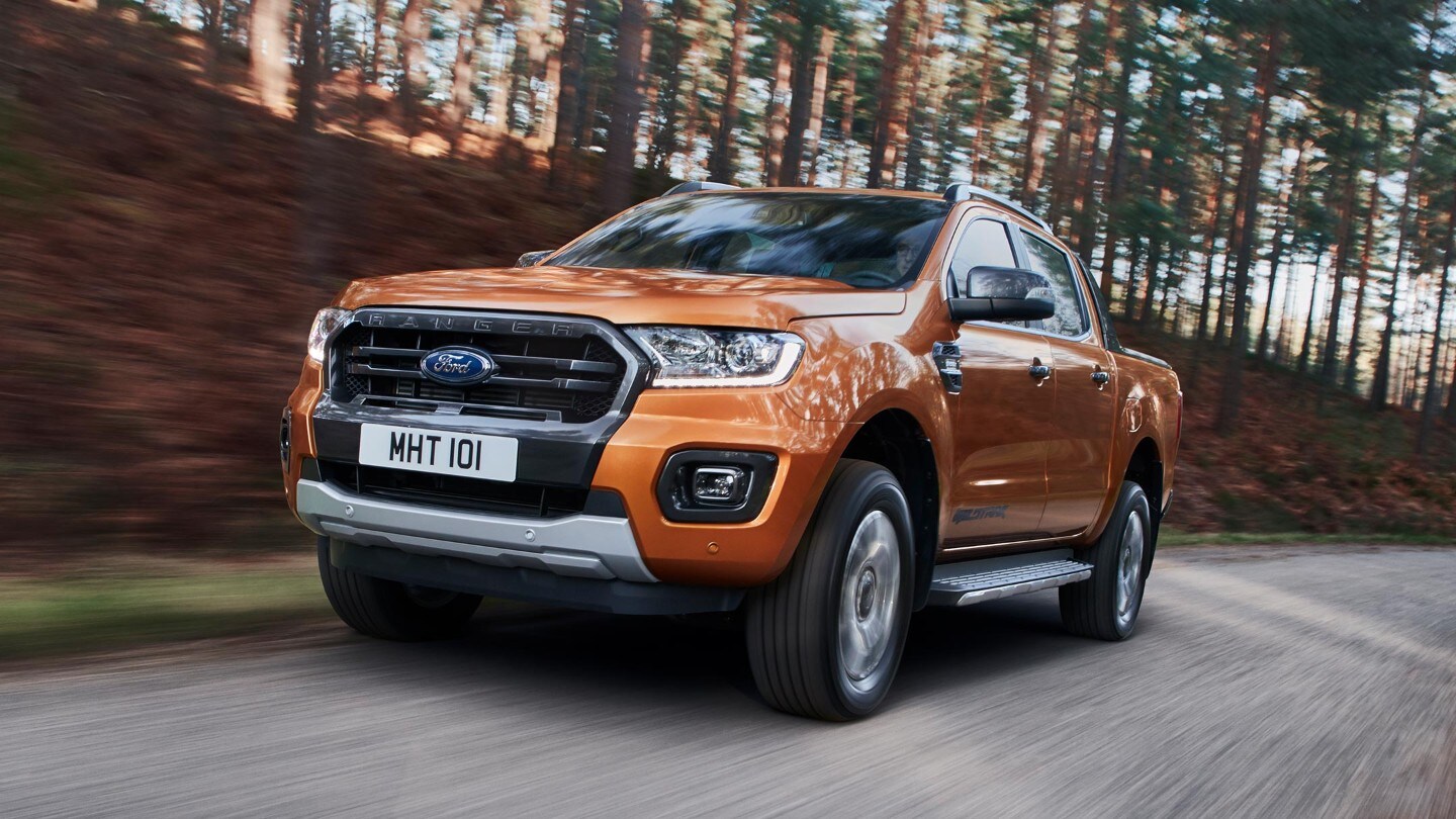 Ford Ranger Wildtrak in Orange. Dreiviertelansicht, fahrend auf einer Forststraße