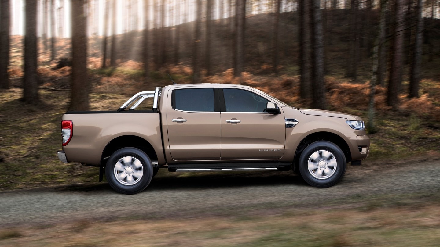 Ford Ranger Limited in Silber. Seitenansicht, fahrend auf einer Forststraße