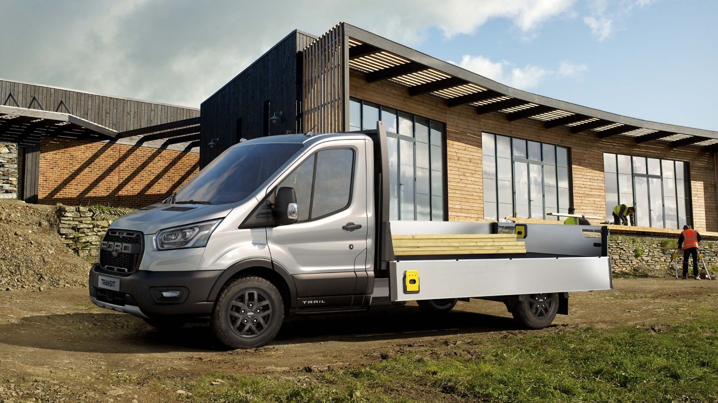 Ford Transit Pritschenwagen in Silber. Seitenansicht, beladen parkt auf Baustelle