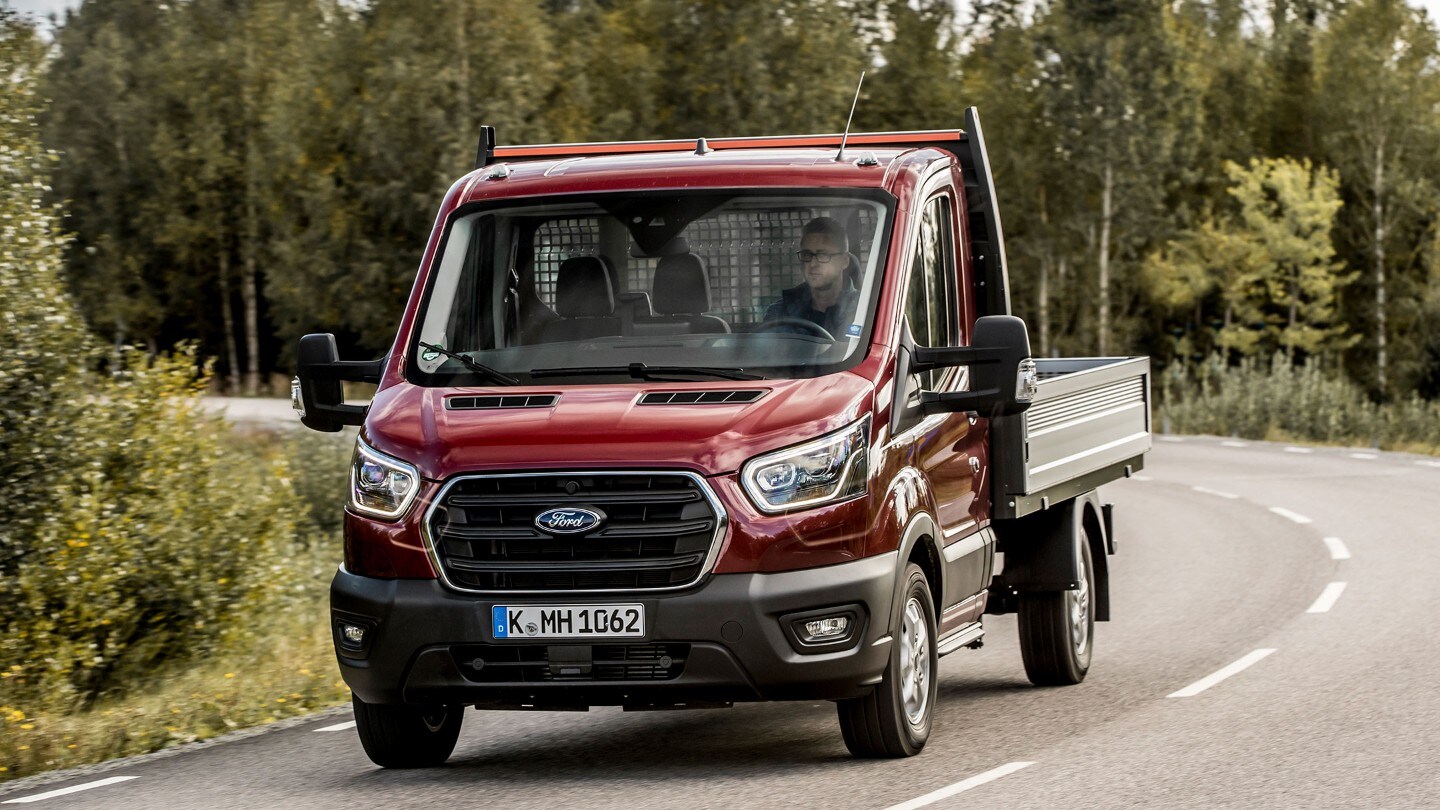 Ford Transit Fahrgestell in Rot. Frontansicht, auf Landstraße fahrend