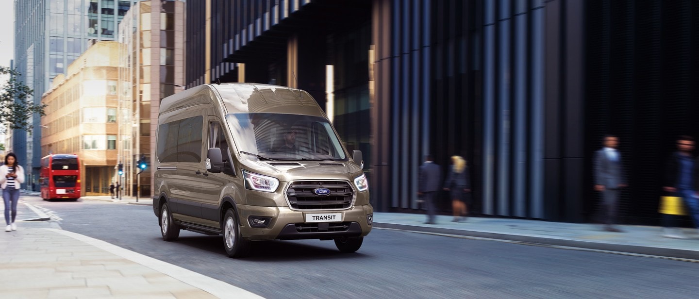 Ford Transit Bus in Silber. Frontansicht, fährt in einer Innenstadt