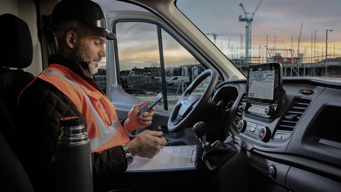 Arbeiter auf einer Baustelle mit Mobiltelefon in der Hand