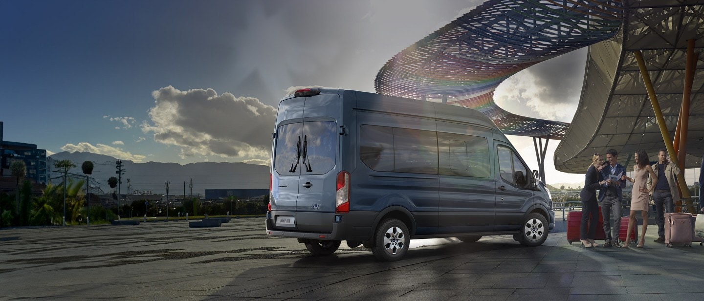 Ford Transit Bus in Blau. Heckansicht, parkt vor einem Flughafen.