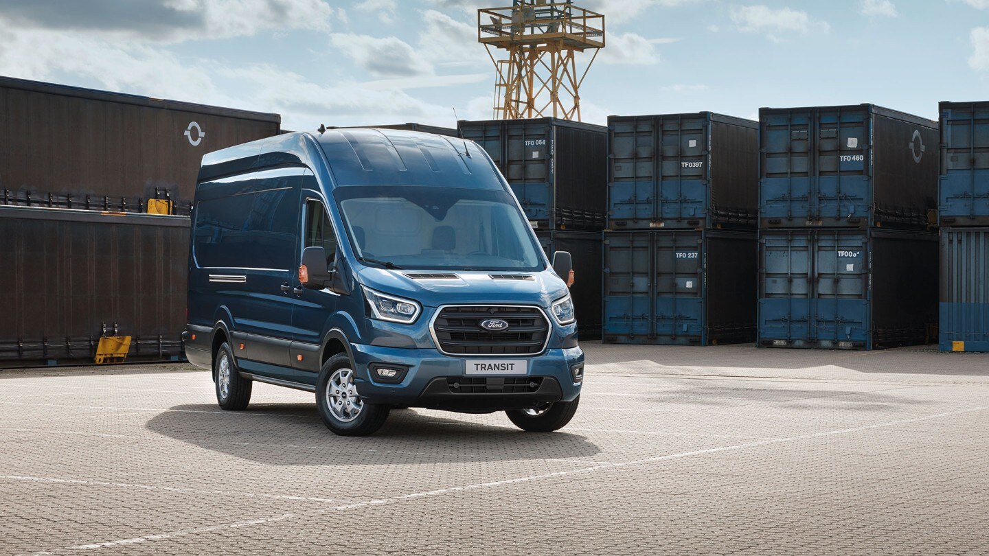 Ford Transit Kastenwagen in Blau. Dreiviertelansicht von vorne, parkend vor Container in einem Hafen