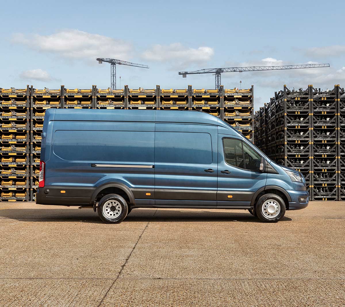 Ford Transit 5 Tonne Kastenwagen LKW in Blau. Seitenansicht, parkend auf einem Betriebsgelände vor Palettenstapeln