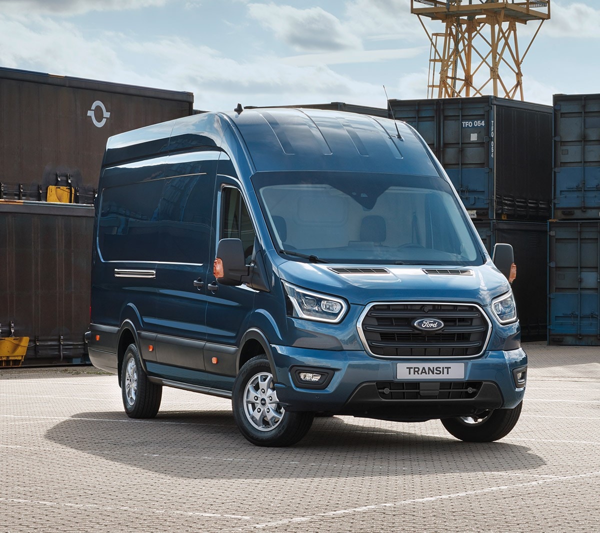 Ford Transit Kastenwagen in Blau. Dreiviertelansicht von vorne, parkend vor Container in einem Hafen