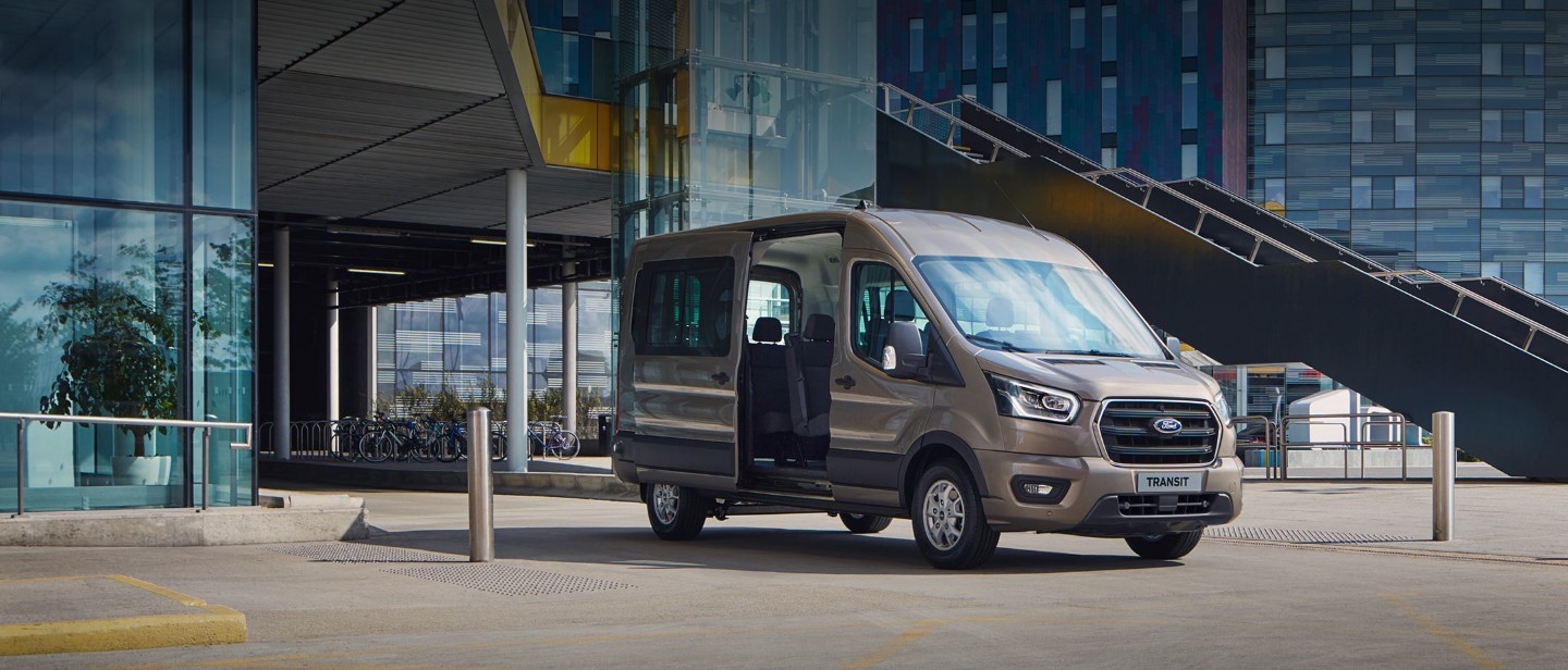 Ford Transit Kombi parkt vor einem modernen Gebäude