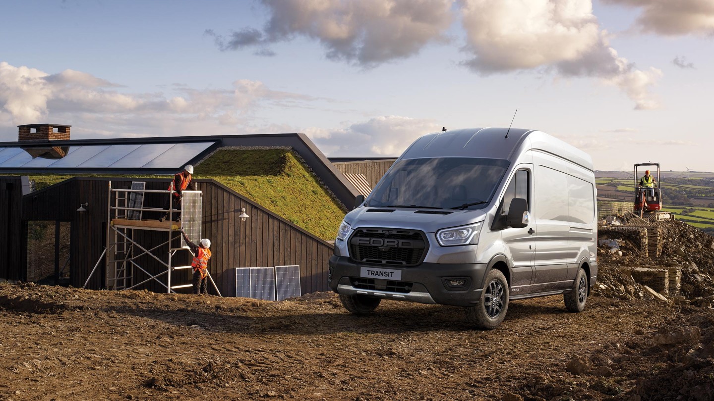 Ford Transit Kastenwagen Trail in Silber. Dreiviertelansicht von vorne, parkend auf einer Baustelle in ländlicher Region