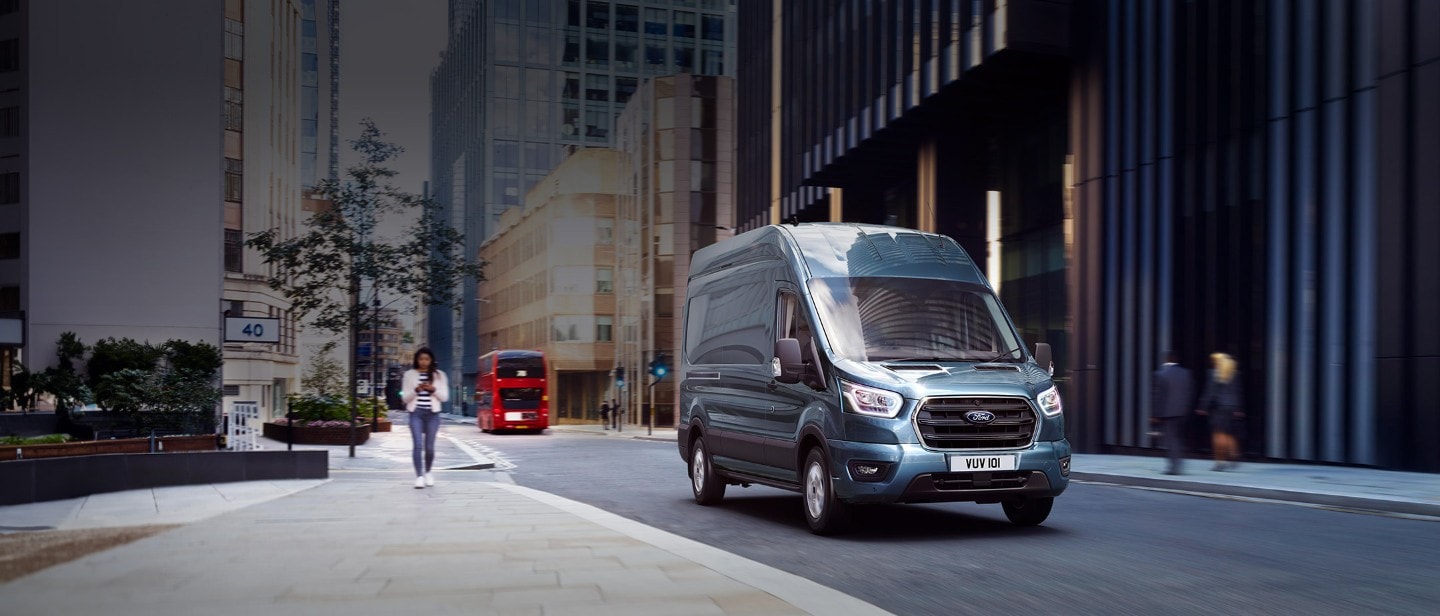 Ford Transit in Blau. Dreiviertelansicht, fahrend durch eine Stadt.