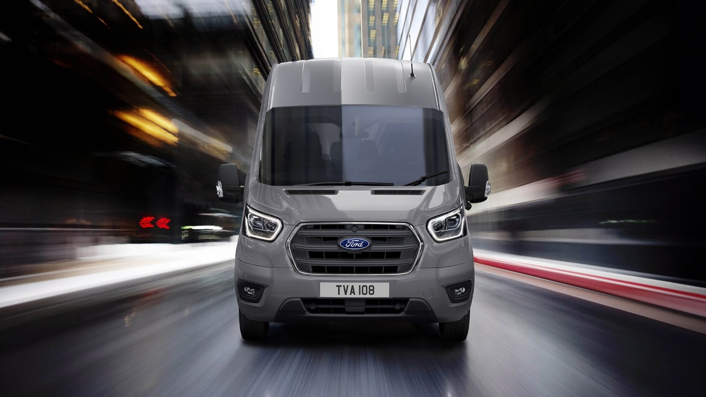 Ford Transit in Grau. Frontansicht, fahrend auf einer Straße.