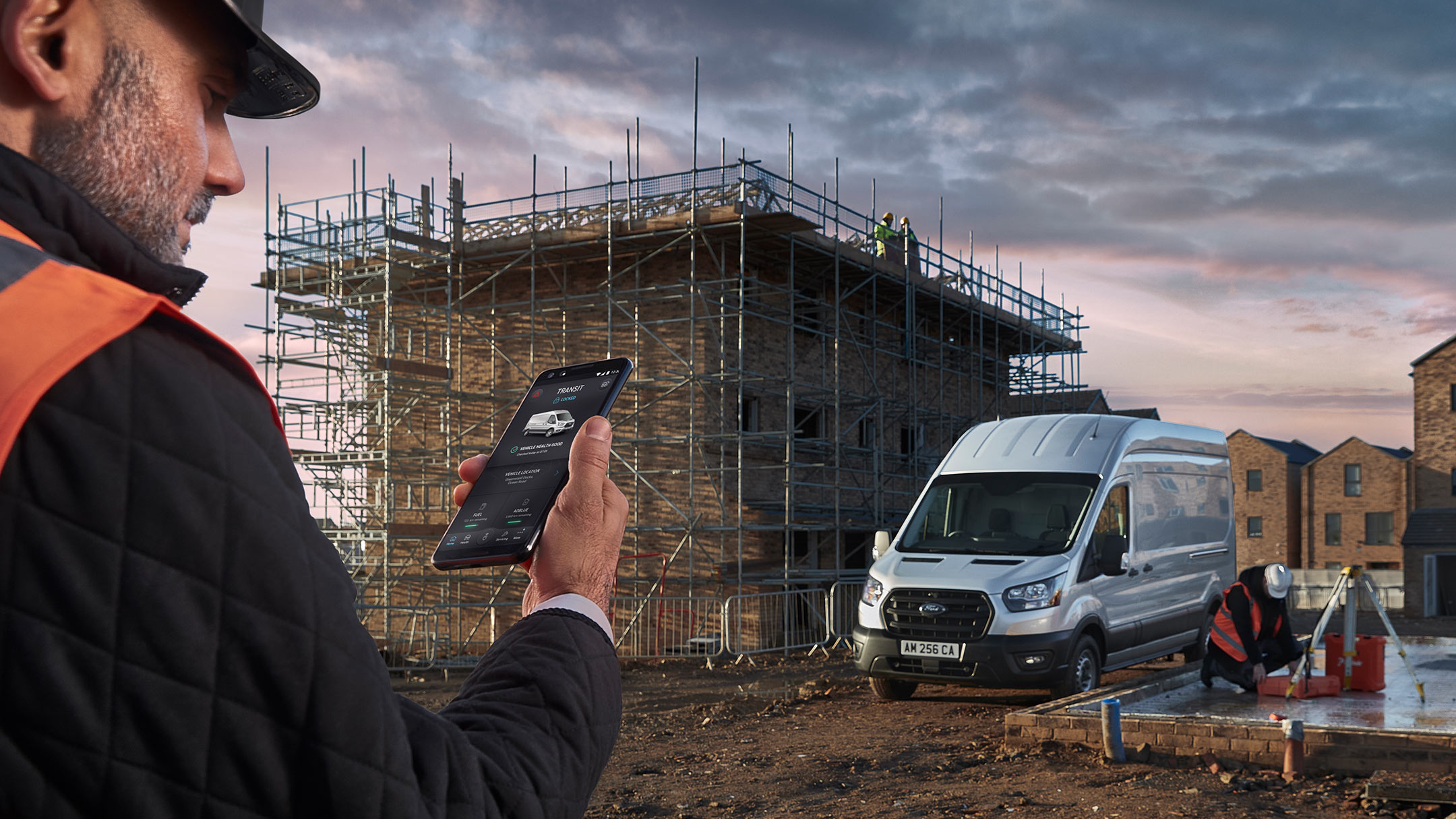 Mann auf einer Baustelle mit Smartphone in der Hand. 