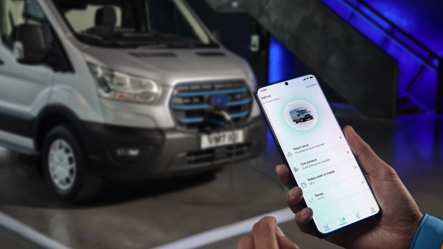 Ford E-Transit in Silber. Frontansicht und Hand, die Smartphone hält