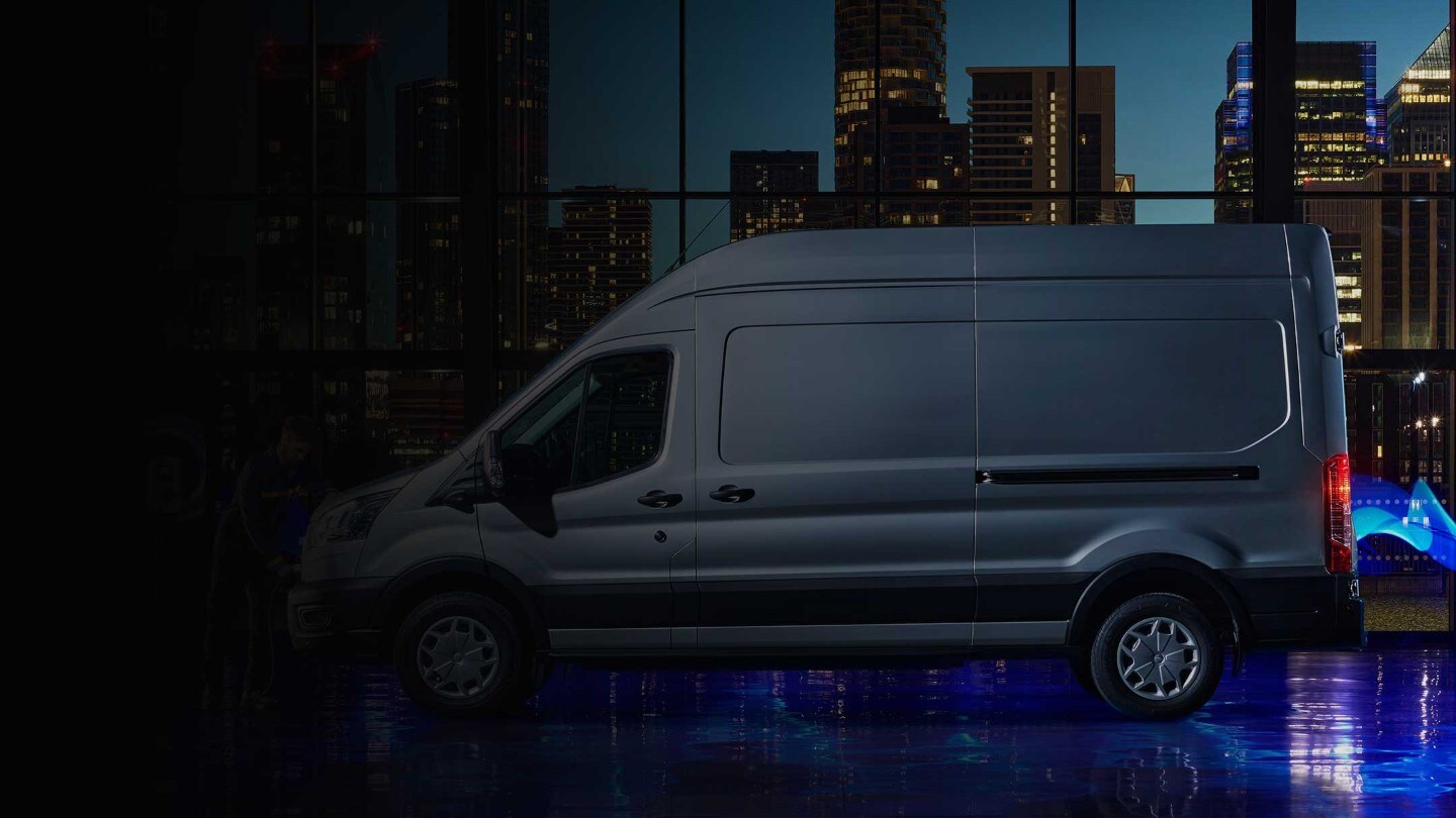 Ford E-Transit in Blau. Seitenansicht, Mann schließt E-Transit an Ladesäule an.