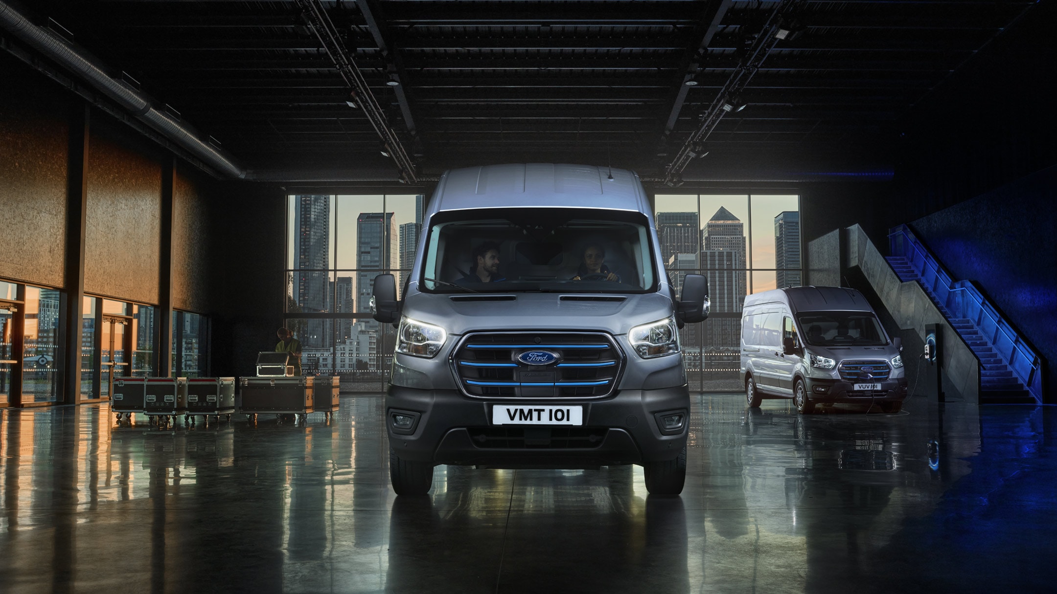 Ford E-Transit in Silber. Frontansicht, parkt in einer Halle.