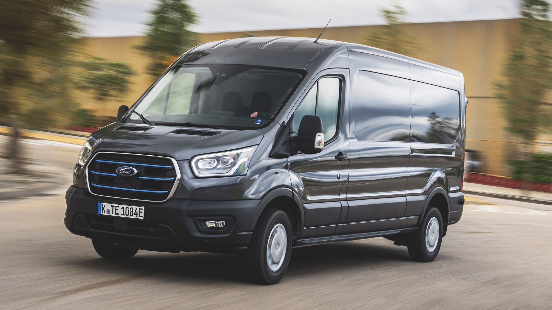 Ford E-Transit in Schwarz. Dreiviertelansicht, fahrend auf einer Straße.