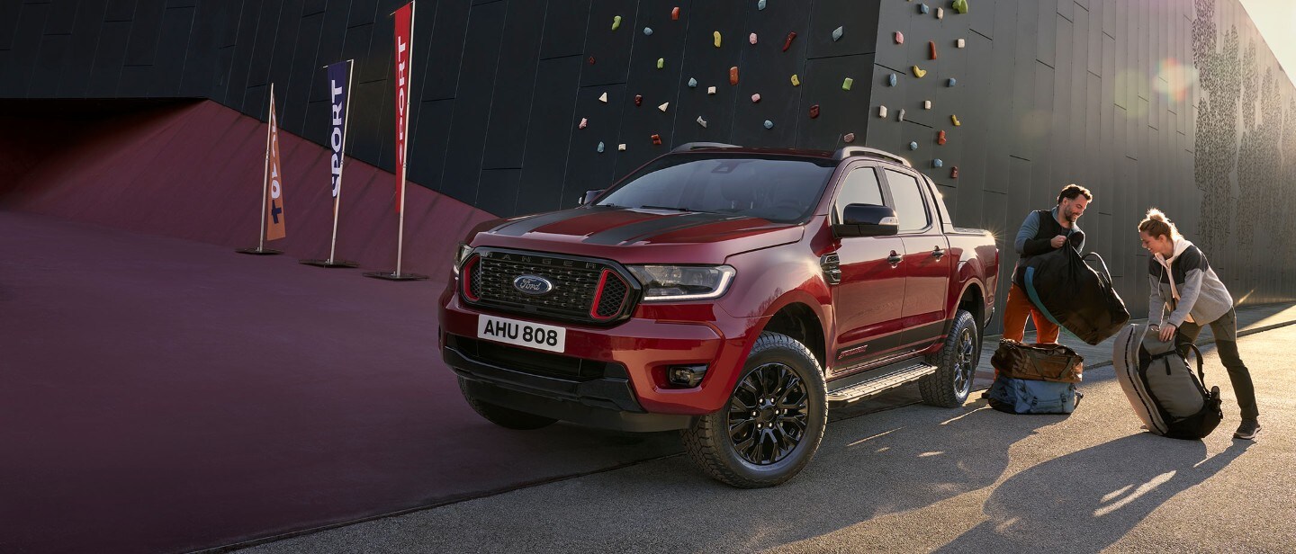 Ford Ranger Stormtrak in Rot. Frontansicht, wird von zwei Personen beladen