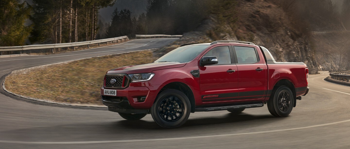 Ford Ranger Stormtrak in Rot. Seitenansicht, bergauf fahrend auf einer Gebirgsstraße