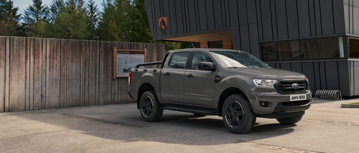 Ford Ranger Wolftrak in Grau. Frontansicht, parkend auf einem Waldweg bei Dämmerung und Nebel