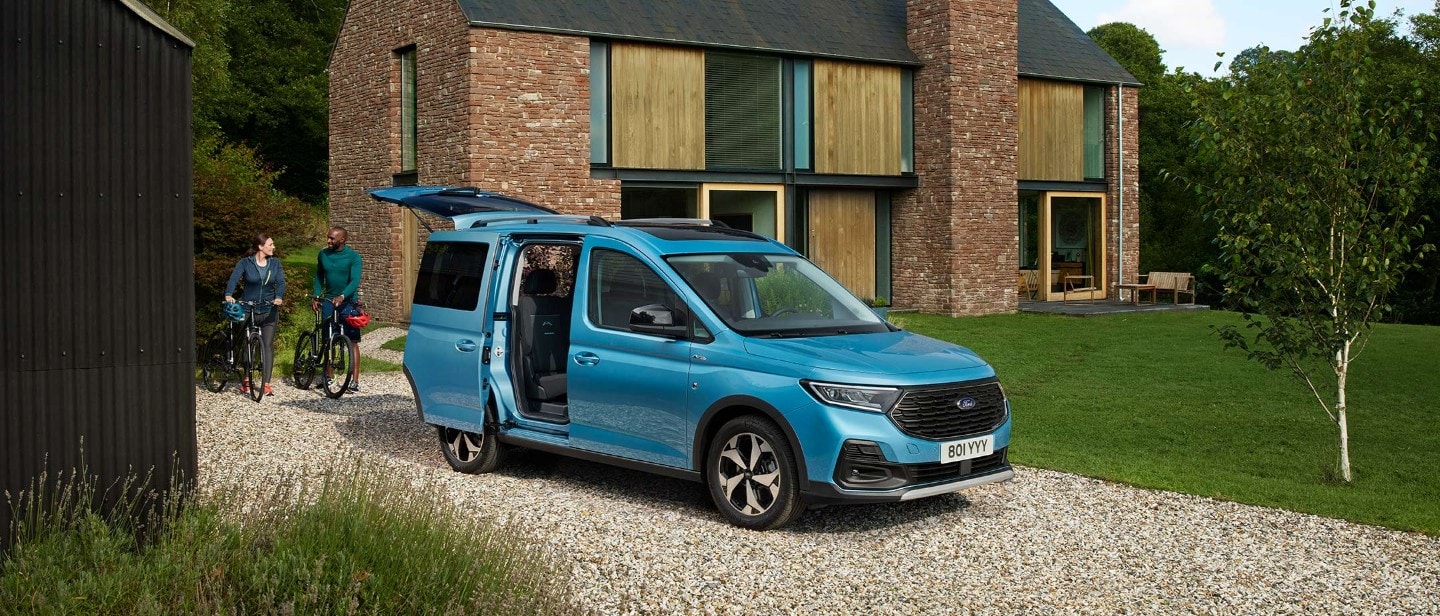 Ford Tourneo Connect in Blau. Dreiviertelansicht, parkt vor einem Haus