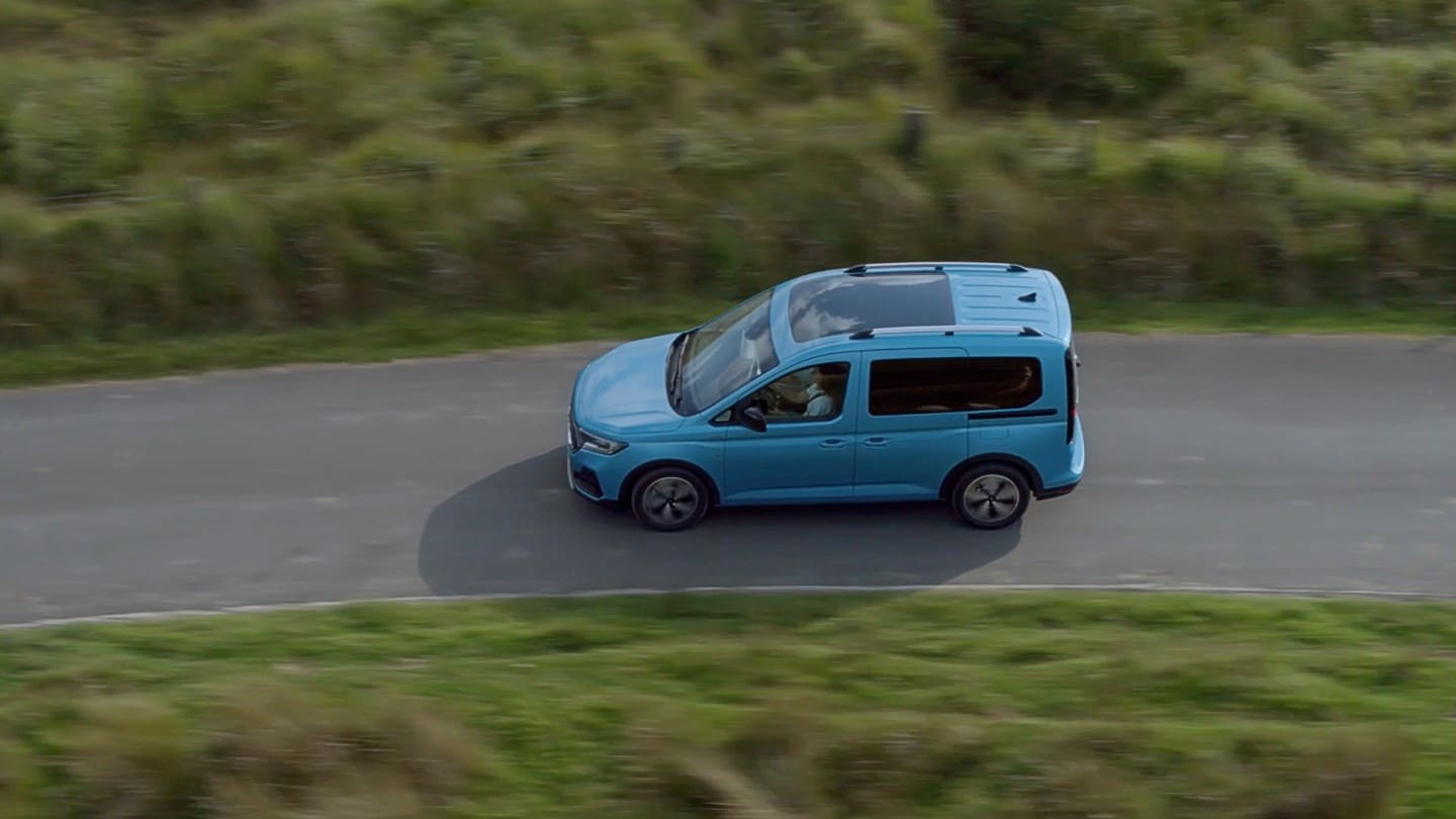 Ford Tourneo Connect in Blau. Vogelperspektive, fahrend auf einer Landstraße.