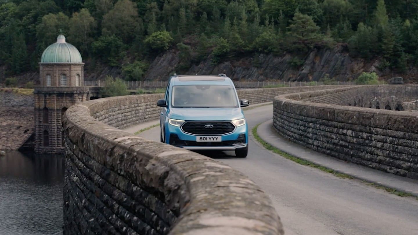 Ford Tourneo Connect in Boundless Blue. Frontansicht, fährt über kurvige Steinbrücke