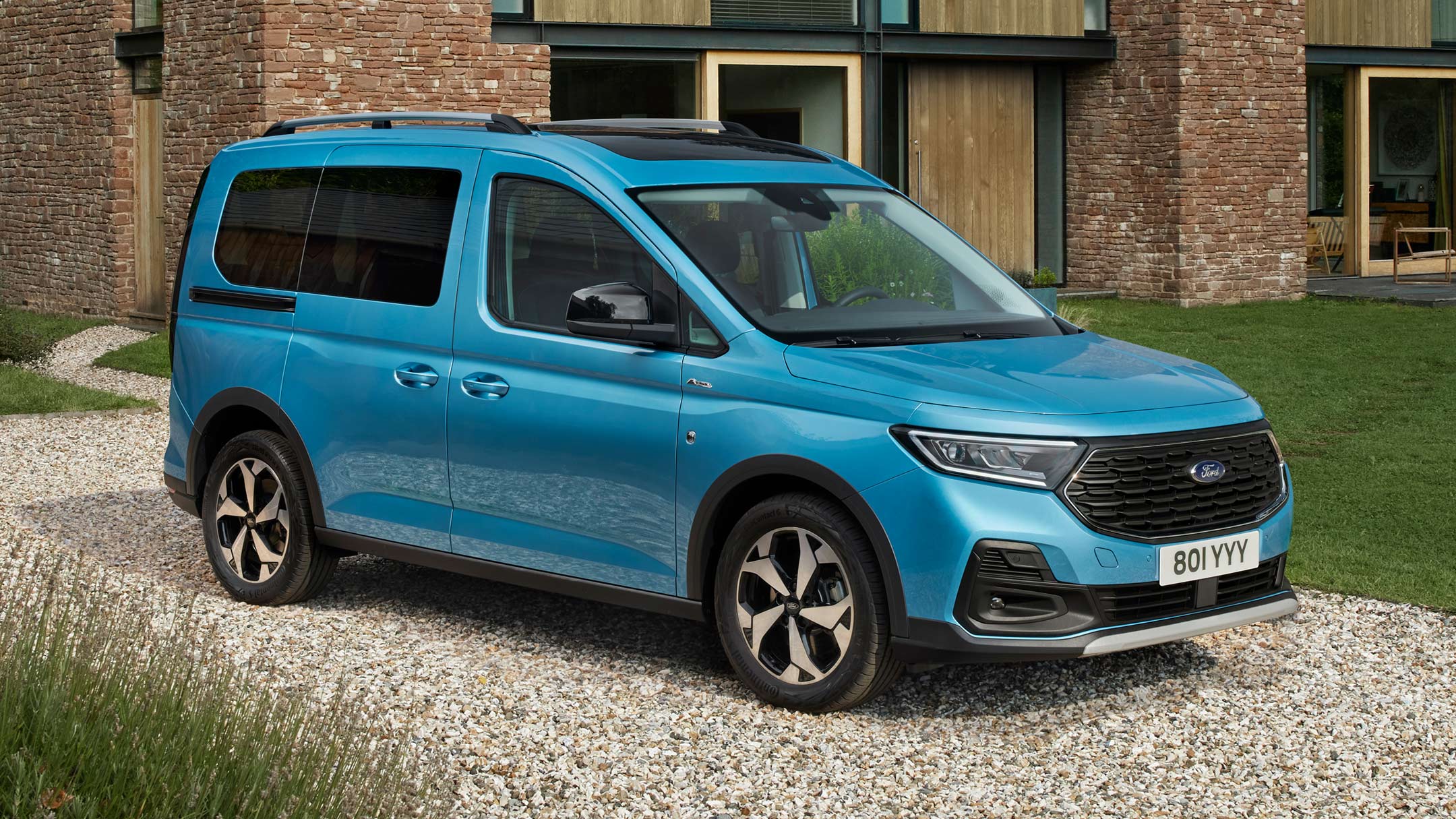 Ford Tourneo Connect in Boundless Blue. Dreiviertelansicht, parkt auf Kiesweg vor Wohnhaus 