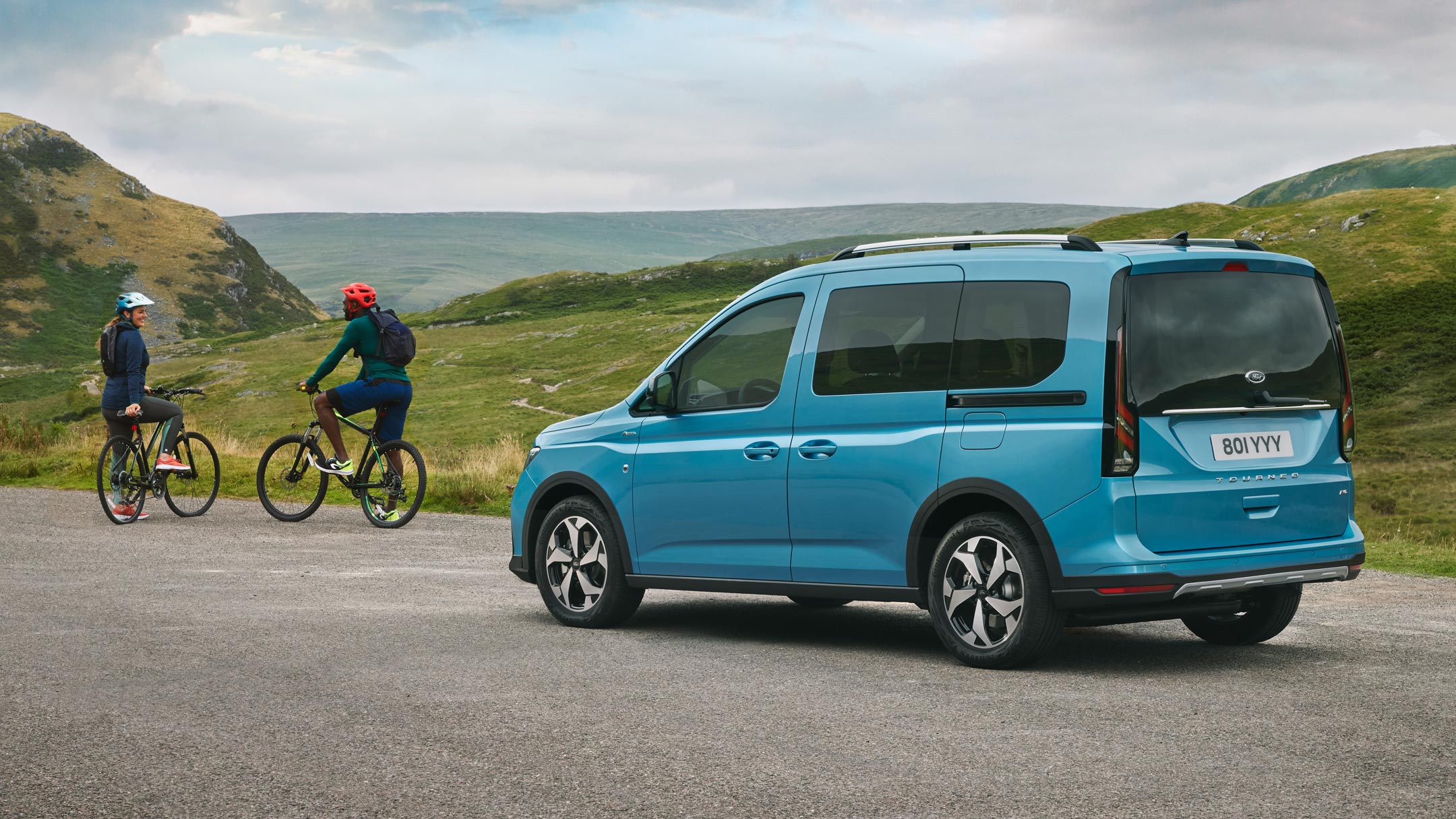 Ford Tourneo Connect in Boundless Blue. Seitenansicht, steht auf Landstraße, davor stehen zwei Fahrradfahrer