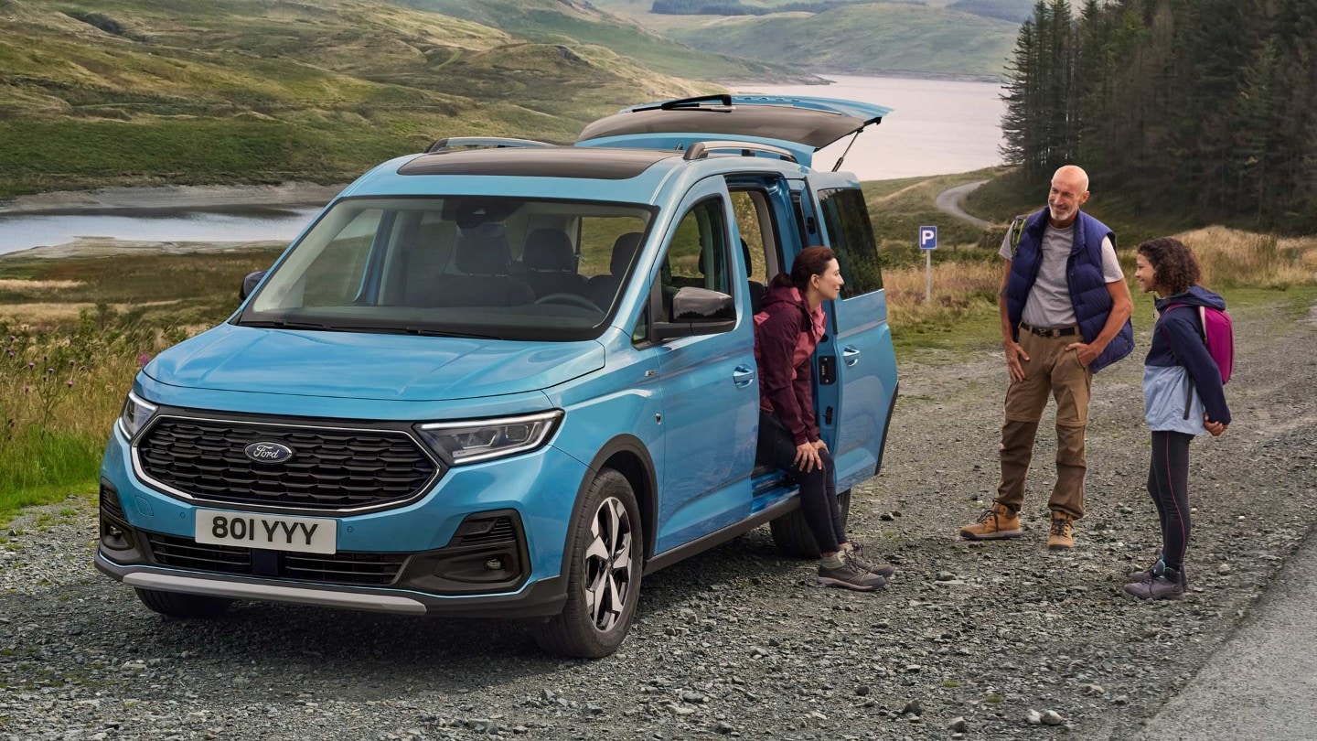 Ford Tourneo Connect in Boundless Blue. Frontansicht, mit geöffneter Schiebetür parkt auf Schotterweg